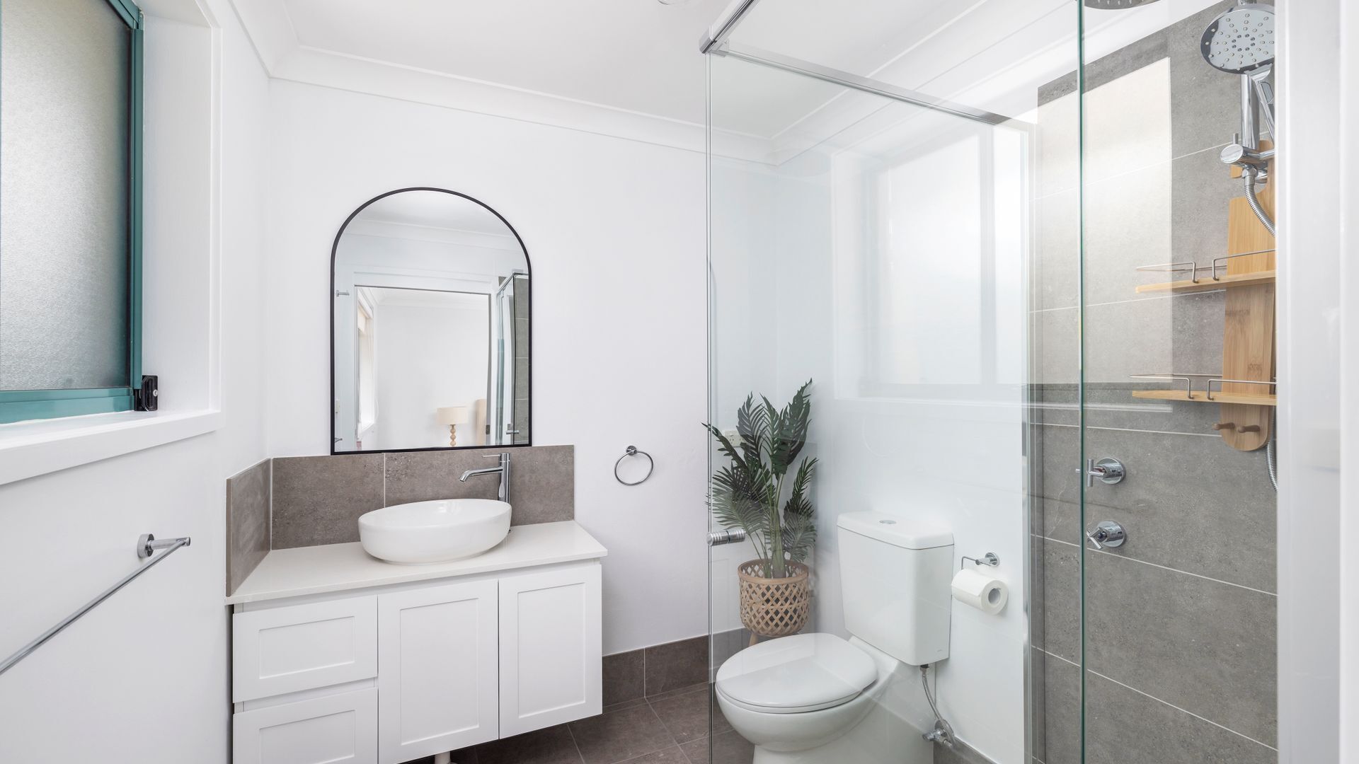 Un baño moderno con cabina de ducha de vidrio, un lavabo blanco y un inodoro.