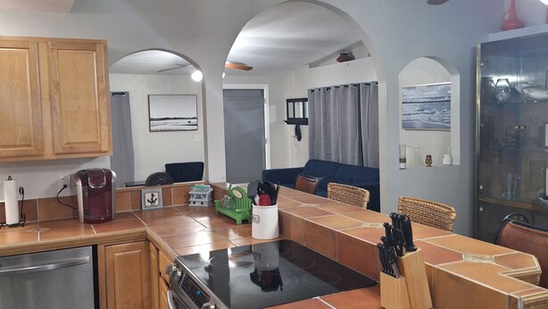 Een moderne keuken met een centraal eiland, houten kastjes en een ingebouwde oven.
