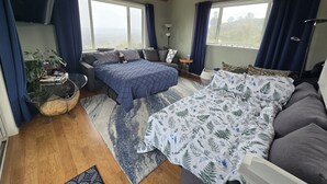 Ein geräumiges Schlafzimmer mit einem großen Bett, einer Couch, einem kleinen Tisch und einem Deckenventilator.