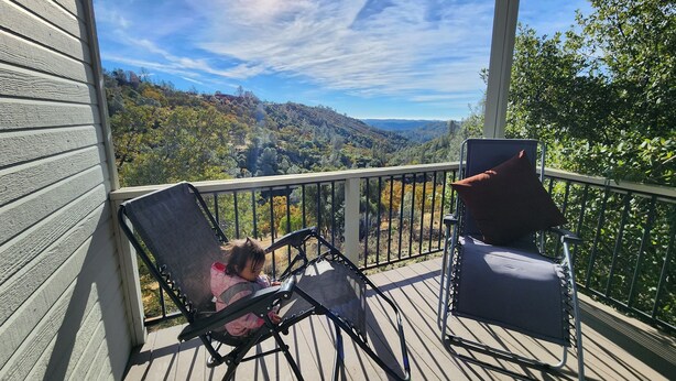 Eine Holzterrasse mit zwei Stühlen und einem Tisch, mit Blick auf eine Berglandschaft.