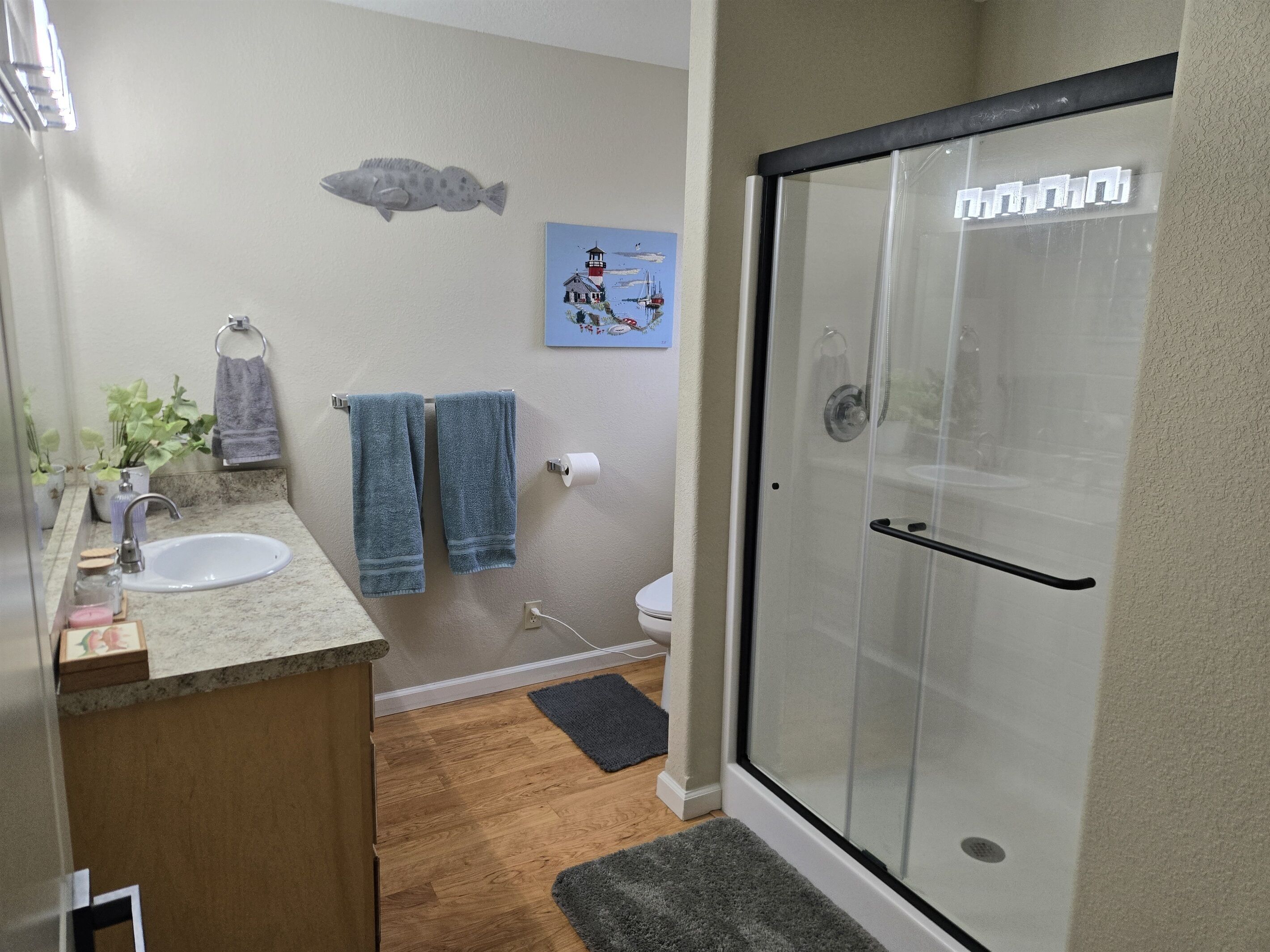 Un baño con lavamanos, toallero, inodoro y cabina de ducha de cristal.