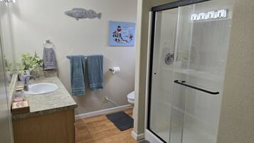 Un baño con lavamanos, toallero, inodoro y cabina de ducha de cristal.