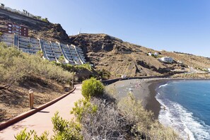 A coastal area with a beach, a staircase leading to a building, and a clear sky.