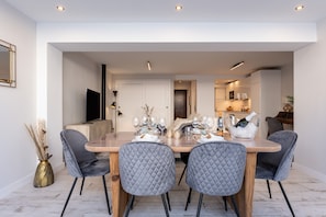 A dining area with a wooden table, grey upholstered chairs, and a white door in the background.