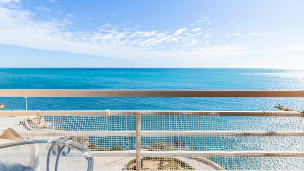A balcony with a clear view of the ocean, a pool, and a netted railing. - Studio Apartment 'Calpe Primera Linea' with Shared Pool, Balcony, and Wi-Fi (Calpe/Calp)