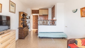 A compact living space with a kitchenette, a television, a wooden dresser, and a sofa. - Studio Apartment 'Calpe Primera Linea' with Shared Pool, Balcony, and Wi-Fi (Calpe/Calp)