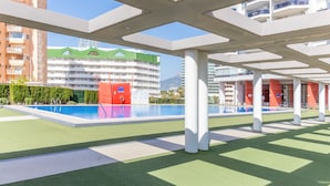 A modern hotel with a pool area, outdoor seating, and a view of surrounding buildings. - Studio Apartment 'Calpe Primera Linea' with Shared Pool, Balcony, and Wi-Fi (Calpe/Calp)