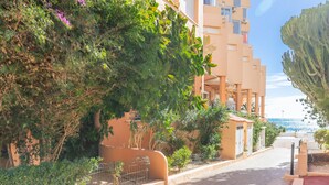 A coastal street with buildings, a clear sky, and a view of the sea. - Studio Apartment 'Calpe Primera Linea' with Shared Pool, Balcony, and Wi-Fi (Calpe/Calp)