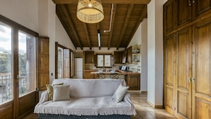 Un salon chaleureux avec un canapé, des meubles en bois et une vue dégagée grâce à de grandes fenêtres.