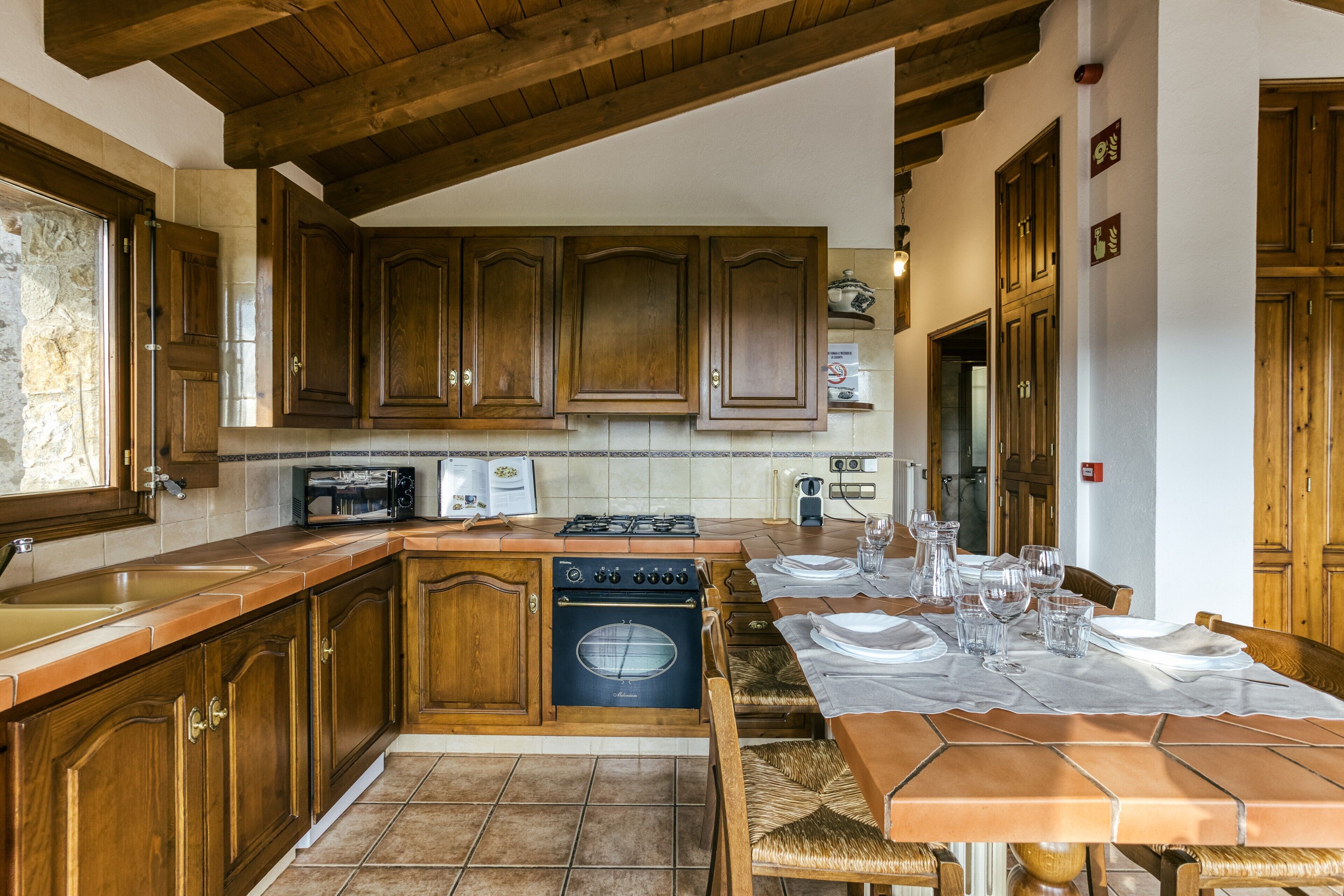Una cocina con armarios de madera, una estufa y una mesa de comedor preparada para seis personas.