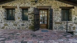Un bâtiment en pierre avec une porte en bois, des fenêtres avec des barreaux en métal et un sol en briques.