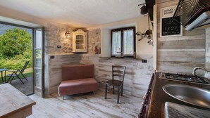 Una cocina acogedora con estufa a gas, un fregadero, un banco de madera y una ventana con vistas a zonas verdes.