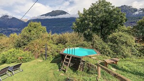 Une piscine entourée d’une végétation luxuriante, avec des montagnes en arrière-plan.