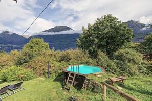 Une piscine entourée d’une végétation luxuriante, avec des montagnes en arrière-plan.
