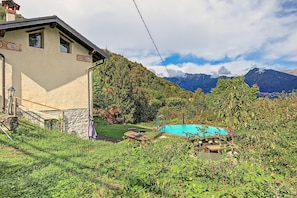 Uma casa com parede de pedra, deck de madeira e piscina rodeada por vegetação.