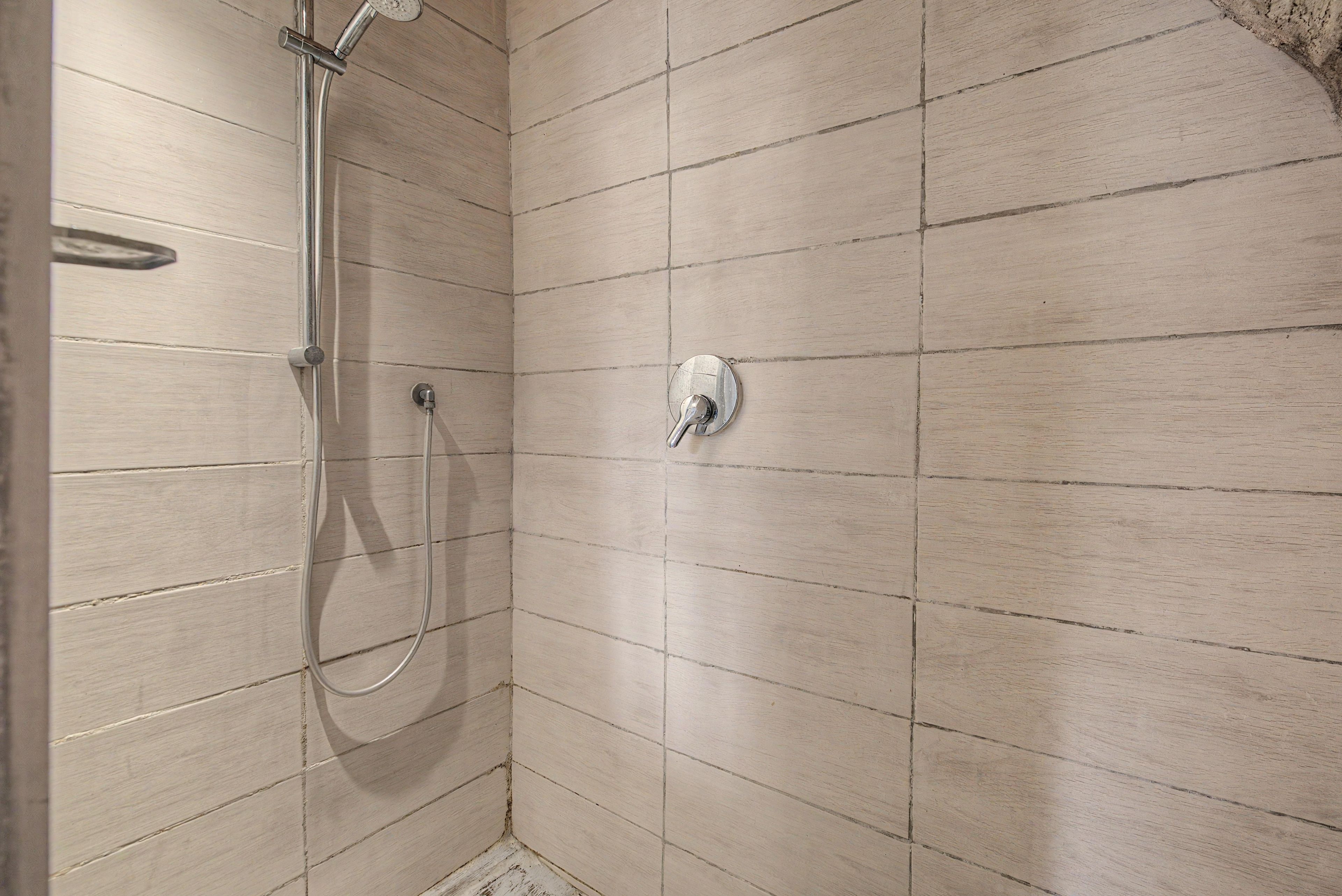 A shower with a handheld showerhead and a wall-mounted control valve.