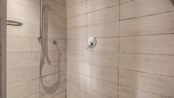A shower with a handheld showerhead and a wall-mounted control valve.
