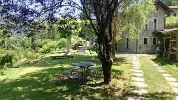 A stone building with a garden, a tree, and outdoor seating.
