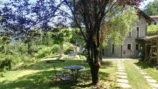 Un bâtiment en pierre doté d’un jardin, d’un arbre et d’un espace extérieur aménagé pour s’asseoir.