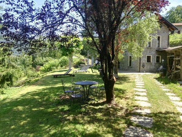 Un bâtiment en pierre doté d’un jardin, d’un arbre et d’un espace extérieur aménagé pour s’asseoir.