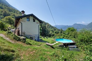 Una casa con piscina, circondata dal verde e dalle montagne.