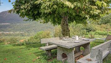 An outdoor stone table with benches, set against a backdrop of a mountainous landscape.