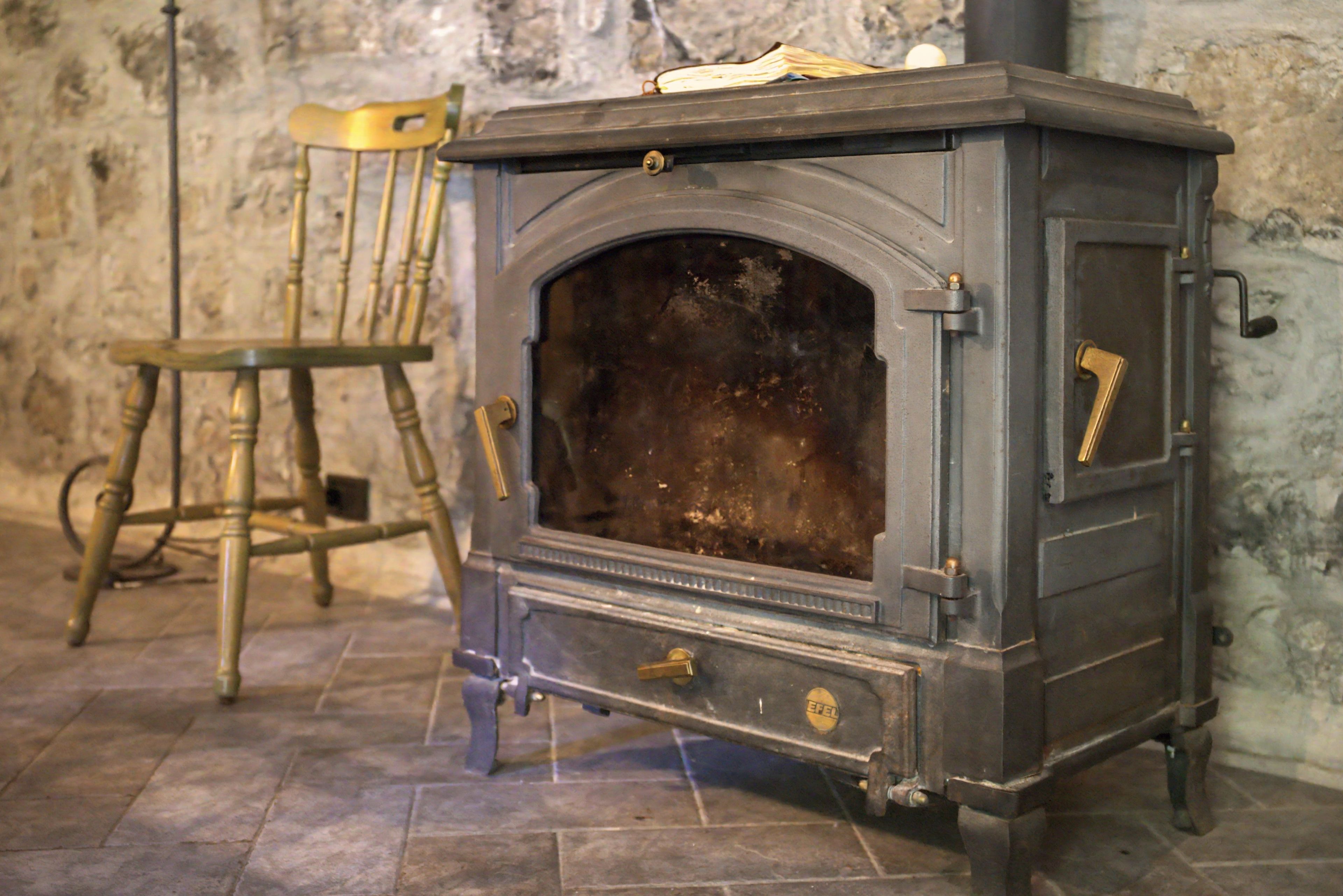 A vintage stove with a wooden chair beside it.