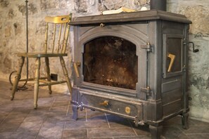 Una estufa antigua con una silla de madera a su lado.