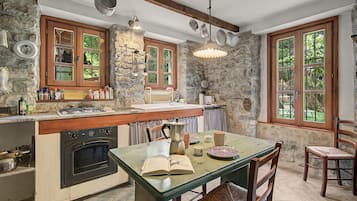 A rustic kitchen with stone walls, wooden cabinets, and a built-in stove.