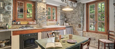 A rustic kitchen with stone walls, wooden cabinets, and a built-in stove.