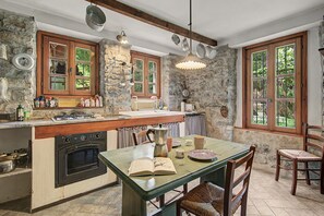 Una cocina rústica con paredes de piedra, armarios de madera y una estufa empotrada.