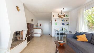 A living room with a fireplace, a dining area, and a sofa with cushions.