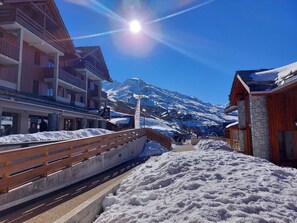 A snow-covered mountain town with wooden buildings, a bridge, and a clear blue sky. - Apartment "Valmeinier 1800" with Mountain View & Shared Pool (Valmeinier)
