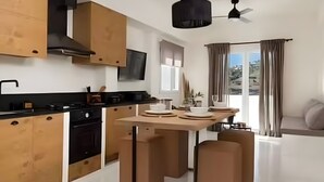 A modern kitchen with wooden cabinets, a black countertop, and a central island with stools. - Apartment 'Batsi View House' with Sea View, Wi-Fi and Air Conditioning (Andros)