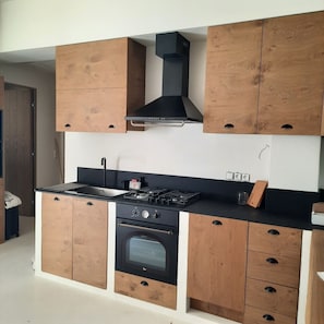A kitchen with wooden cabinets, a stove, oven, and a black range hood.