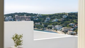 A balcony with a view of a coastal town, a potted plant, and a marble sculpture. - Apartment 'Batsi View House' with Sea View, Wi-Fi and Air Conditioning (Andros)