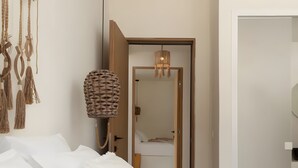A bedroom with a bed, a door leading to another room, and a wall-mounted lamp. - Apartment 'Batsi View House' with Sea View, Wi-Fi and Air Conditioning (Andros)