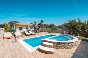 Una piscina con borde de piedra, sillas de descanso y una cubierta de madera.