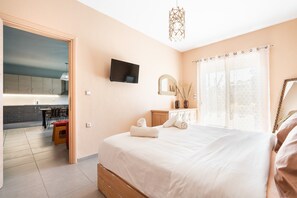 Un dormitorio con una cama, un televisor, un espejo y una ventana con cortinas.