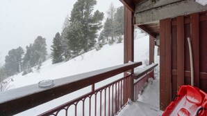 A snowy balcony with a railing, a red sled, and a wooden structure. - Apartment 'Arc 2000' with Mountain View and Balcony (Bourg-Saint-Maurice)