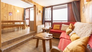 A wooden interior with a red sofa, wooden benches, and a table. - Apartment 'Arc 2000' with Mountain View and Balcony (Bourg-Saint-Maurice)