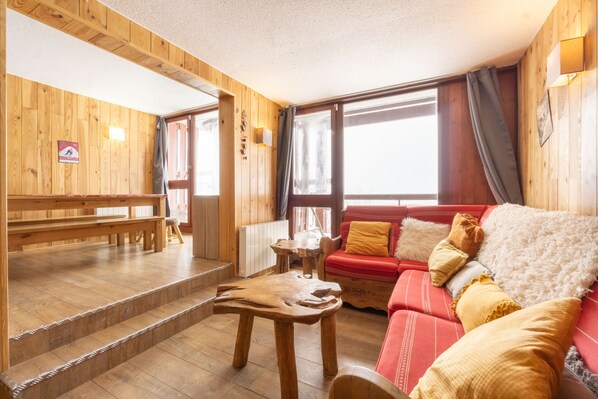 A wooden interior with a red sofa, wooden benches, and a table. - Apartment 'Arc 2000' with Mountain View and Balcony (Bourg-Saint-Maurice)