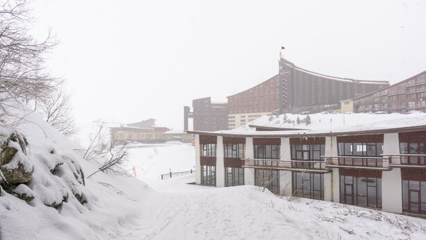 A snow-covered building with a curved facade, large windows, and a flat roof. - Apartment 'Arc 2000' with Mountain View and Balcony (Bourg-Saint-Maurice)