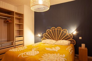 A bedroom with a bed featuring a unique leaf-shaped headboard, a wooden wardrobe, and a hanging light fixture.