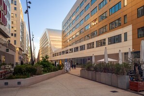 A modern urban street with buildings, outdoor seating, and a clear sky. - Apartment "Porte Bleue" with Sea View, Private Terrace & Wi-Fi (Marseille)