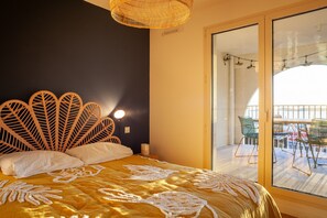 A room with a bed, a wall-mounted light, a window, and a view of an outdoor area with chairs. - Apartment "Porte Bleue" with Sea View, Private Terrace & Wi-Fi (Marseille)