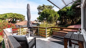 Varanda com banco de madeira, mesa e guarda-sol.