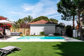 Un giardino sul retro con piscina, una piccola costruzione e un prato.