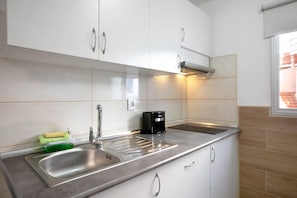Una cocina moderna con electrodomésticos de acero inoxidable, un lavamanos doble y armarios blancos.