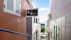 Un callejón estrecho con un letrero del hotel 'La Morena', una baranda metálica y vistas al mar.